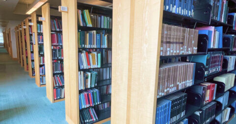 Eight long library shelves filled with different colored books.